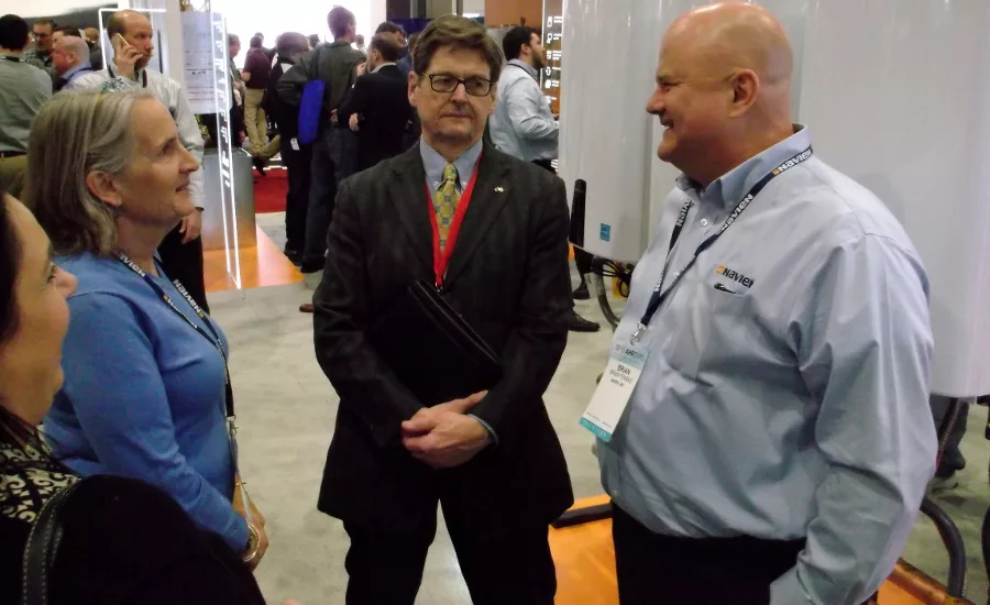 BNP Plumbing Group publisher Bob Miodonski, center, chats with Ann Woodard and Brian Fenske about Navien and its place in the water heater market