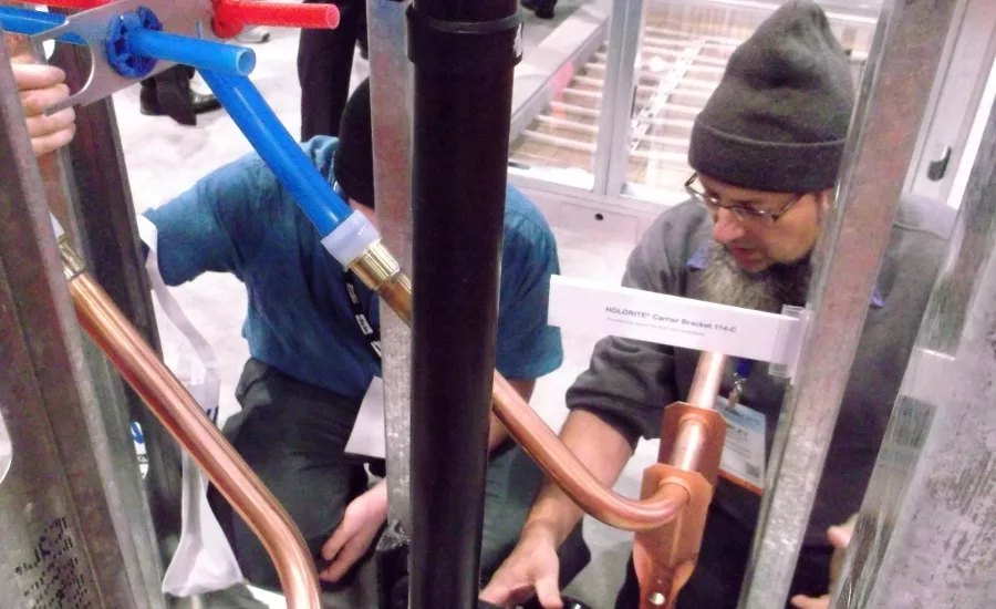 A pair of contractors talk over the uses of PEX and accompanying bracketry during a visit to Uponor’s booth at the AHR Expo in Las Vegas, Jan. 31-Feb. 1