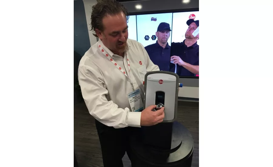 Rheem Mfg. Co.’s Matt Lamasney poses with one of the company’s new individual tankless water heaters at the 2017 AHR Expo in Las Vegas