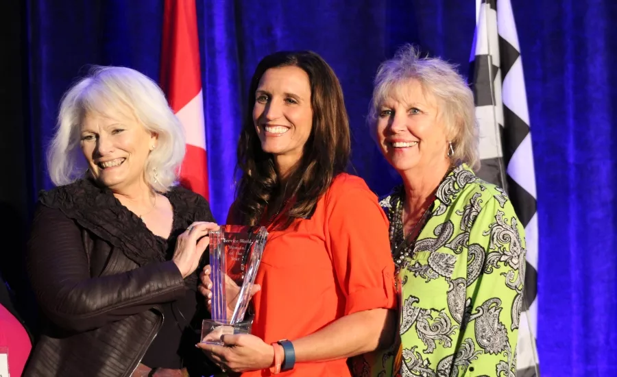 Angie Snow (center), owner and vice president of Western Heating and Air Conditioning in Boise, Idaho, receives the inaugural Woman of the Year award during Service World Expo in Las Vegas