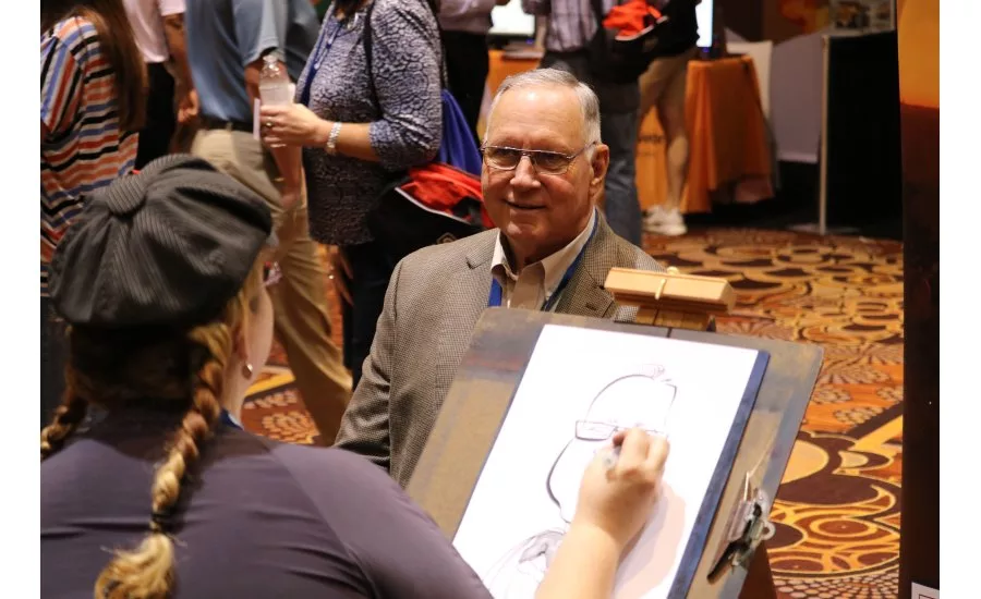 An artist draws caricatures of Service World Expo attendees at the Women in HVACR booth during the expo event