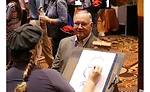 An artist draws caricatures of Service World Expo attendees at the Women in HVACR booth during the expo event