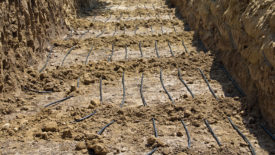 A trench filled with plastic tubing used for the installation of a geothermal residential heating and cooling system.