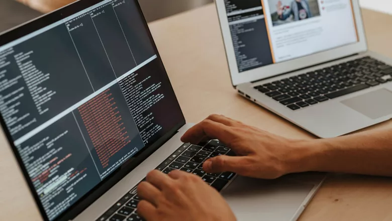 A person typing on a computer, with another computer beside them.