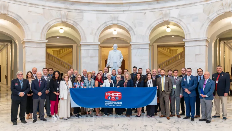 PHCC members with a banner in a government building. 