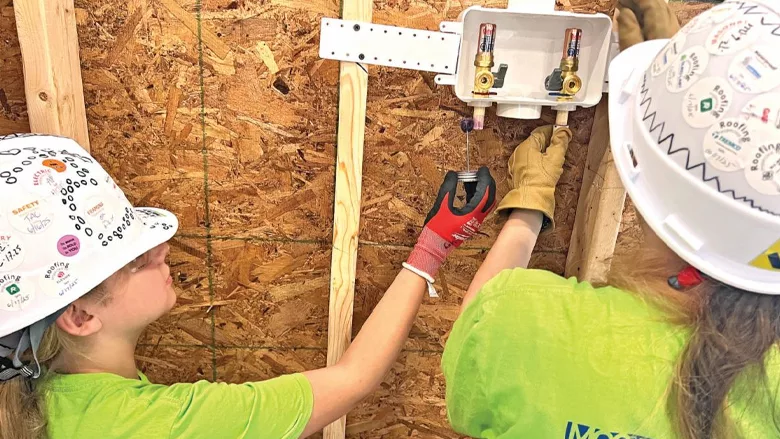 Two young girls work together at the construction camp.