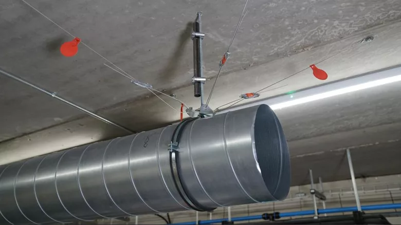 An HVAC duct seismically braced using a cable system.