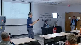 A Rheem representative in front of a presentation with several attendees. 