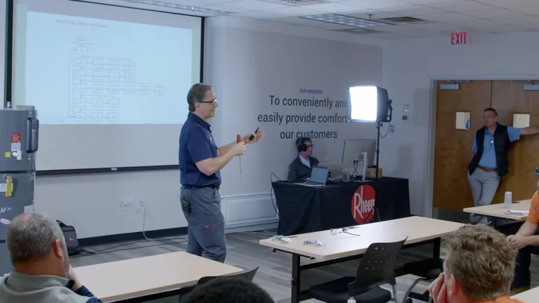 A Rheem representative in front of a presentation with several attendees.