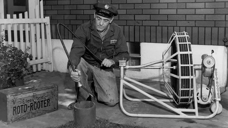 A classic picture of a tech using an electric Roto-Rooter. 