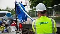 A person in a hardhat and a construction vest with "Uponor" on the back. 