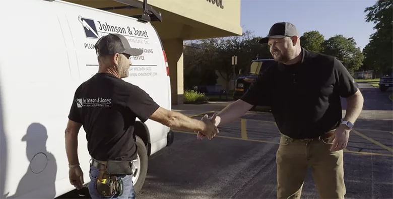 A technician from Johnson & Jonet shakes hands with a school official. 