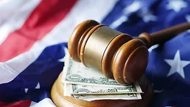 A gavel above money, all set over the American flag. 