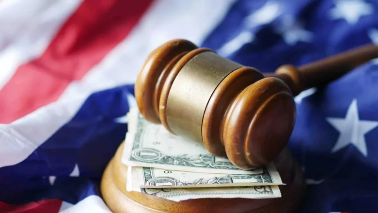 A gavel above money, all set over the American flag. 