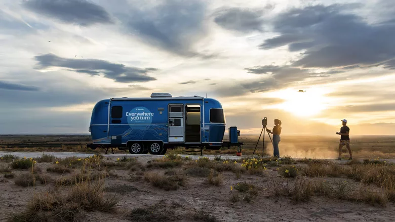 The Trimble branded airstream on the road, with a person recording it.