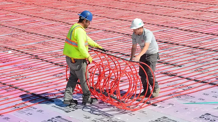 Field installation of RAUMAT showcasing fast-roll placement of pre-assembled radiant circuits