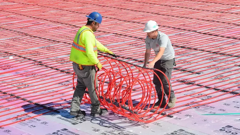 Field installation of RAUMAT showcasing fast-roll placement of pre-assembled radiant circuits