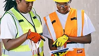 A contractor and apprentice look over documents on a jobsite.