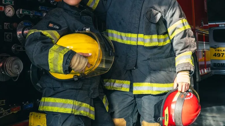 Two firefighters in front of a firetruck.