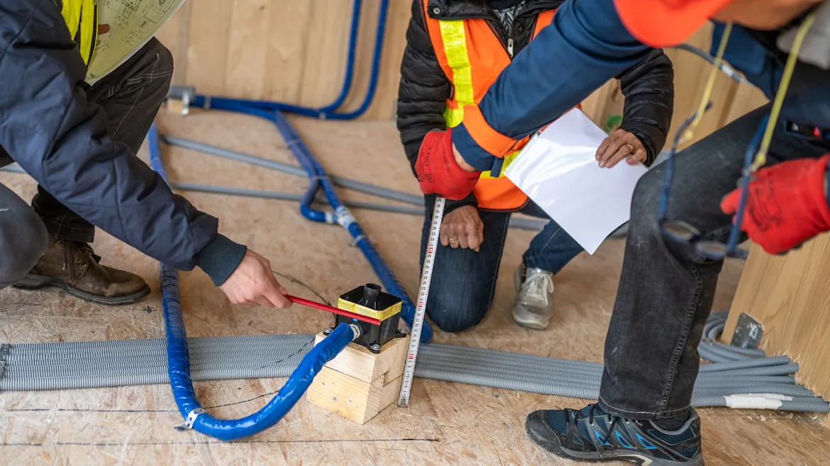 Three Plumbers Discuss Job with Blueprints