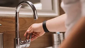 A person turning on a faucet.