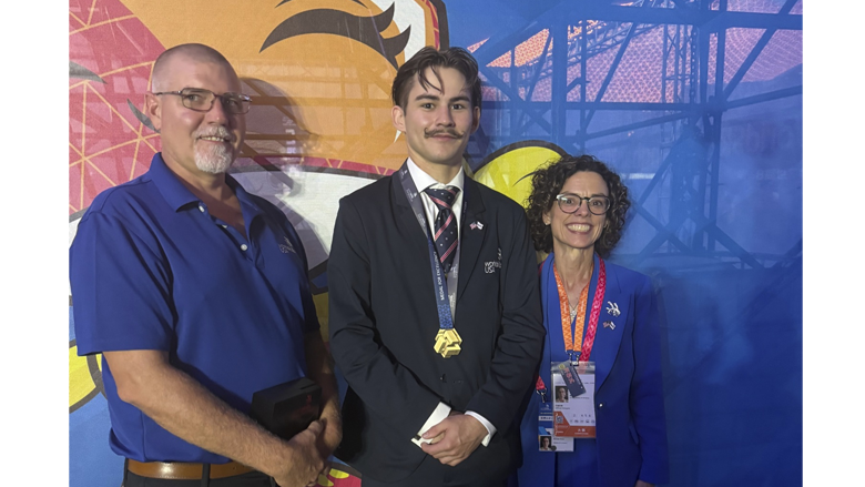 Charles and two other posing with him wearing his Medal of Excellence.