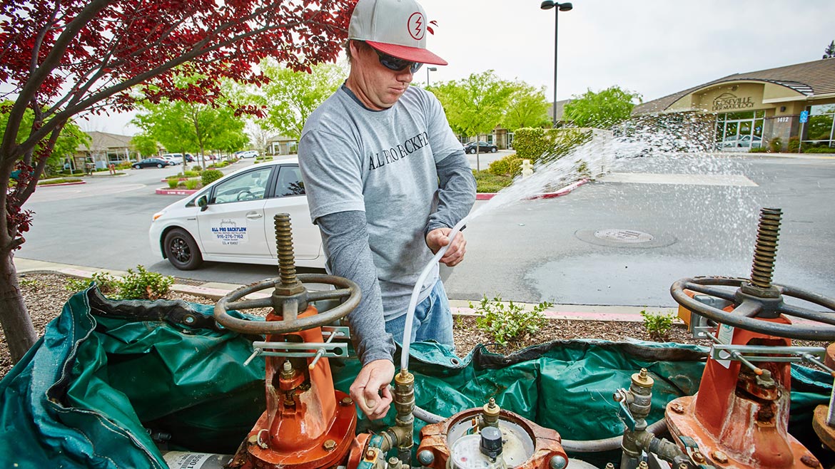 a technician bleeds water out of the backflow assembly