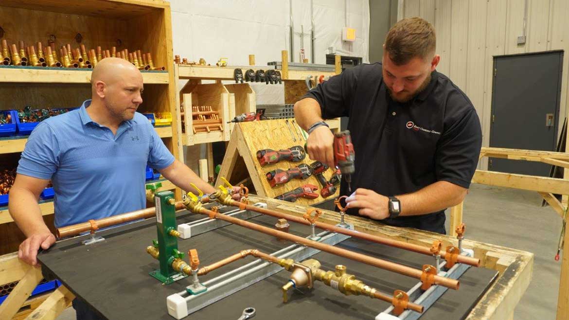 03 PM 1223 FW Webb feature. Mike Leander, F.W. Webb’s Director of Industrial Sales (left) looks on as Jared Dodge, Webb’s lead boiler board technician, assembles a new boiler board at Webb’s Process Controls Division in Winslow, Maine.