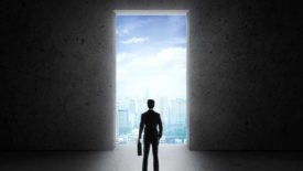 PM Jan 2024 Matt Michel column opening image of businessman standing in front of large door with a view to the city