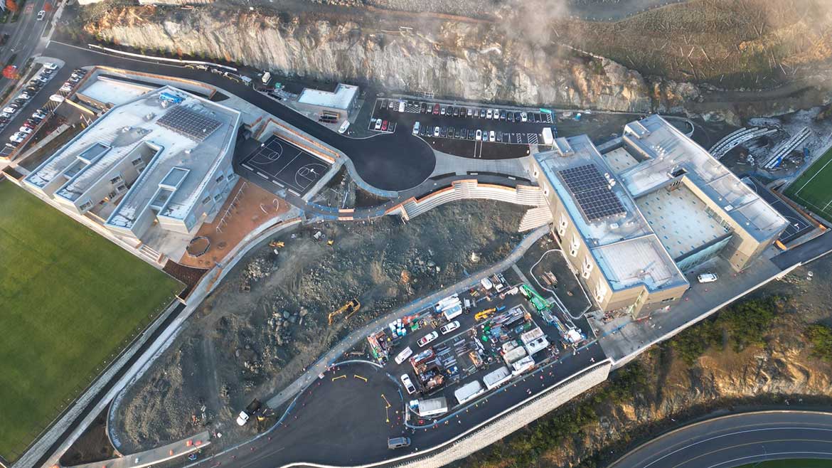 Aerial view of Vancouver Island Schools complex of two buildings, parking lots and construction area in the center.