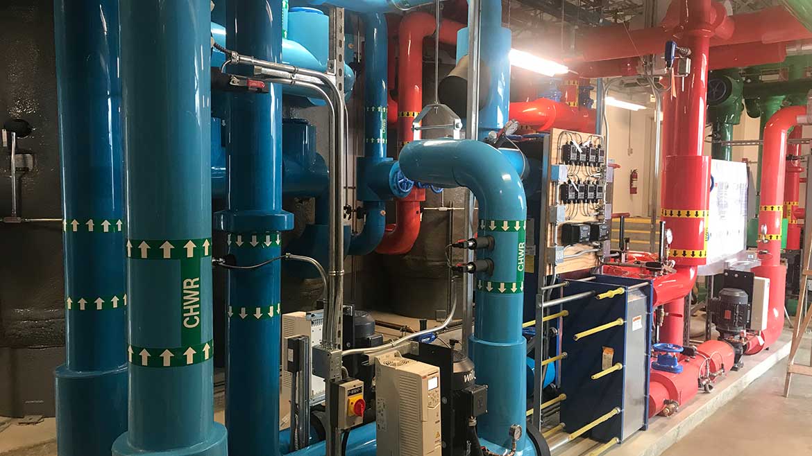 Vancouver Island Schools central plant is visible for educational purposes. The plant was designed to be a learning hub, including features such as color-coded pipes and a TV dashboard that displays plant data.
