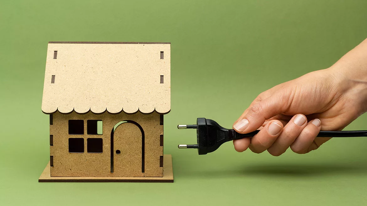 PME March 2024 John Siegenthaler Column feature image of an electric plug being plugged in to a small wooden model house.