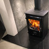 Image of square cast iron woodburner on top of granite slab with orange fire flames burning.