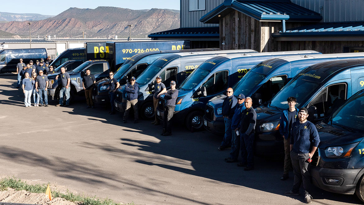 PSI team group photo posing in front of PSI trucks and vans.