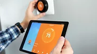 Temperature adjustment using a tablet Man is Adjusting a temperature using a tablet with smart home app in modern living room.