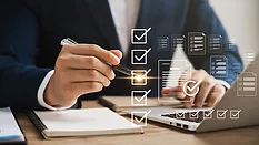 Businessman using a laptop with virtual online survey with digital forms and checklists floating above it.