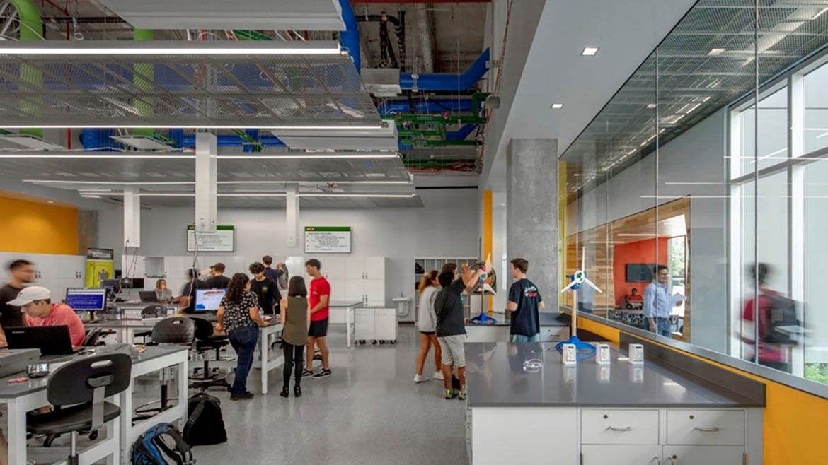 A classroom full of students showing a combined open and perforated ceilings with color-coded piping.