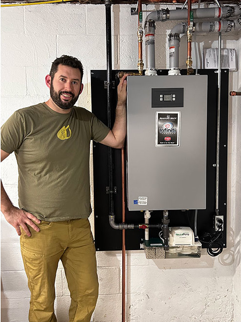 Man posing next to an installed tankless water heater.