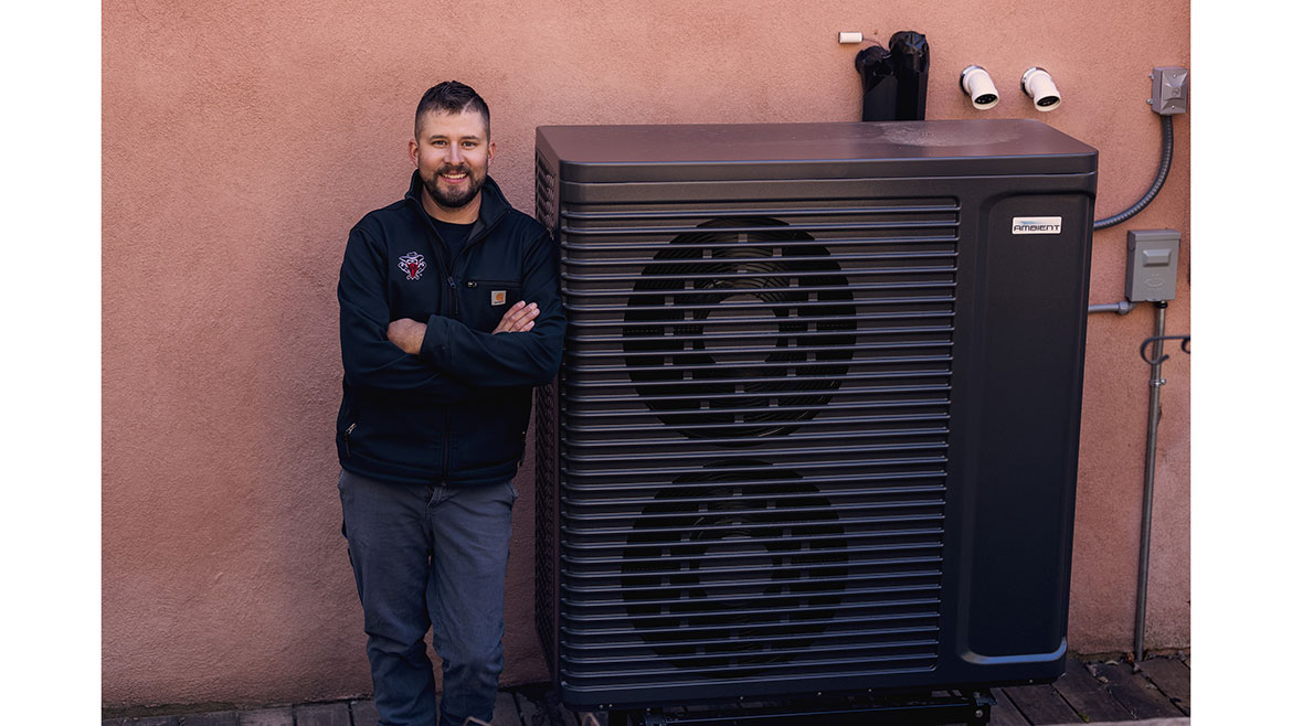Keefer Rader, owner of Outlaw Mechanical posting next to hydronic heat pump.