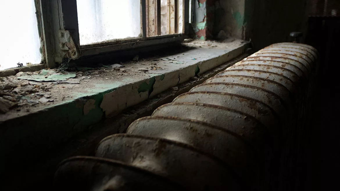 A dilapidated window, window sill, and radiator.