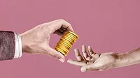 The arm of a businessman gives gold coins to another cropped arm of a man The arm of a businessman gives gold coins to another cropped arm of a man.
