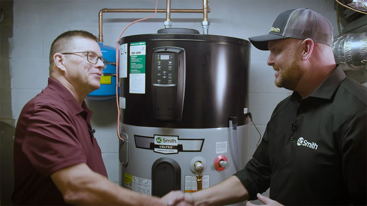 AO Smith technician shaking hands with a man standing by a heat pump water heater(HPWH).