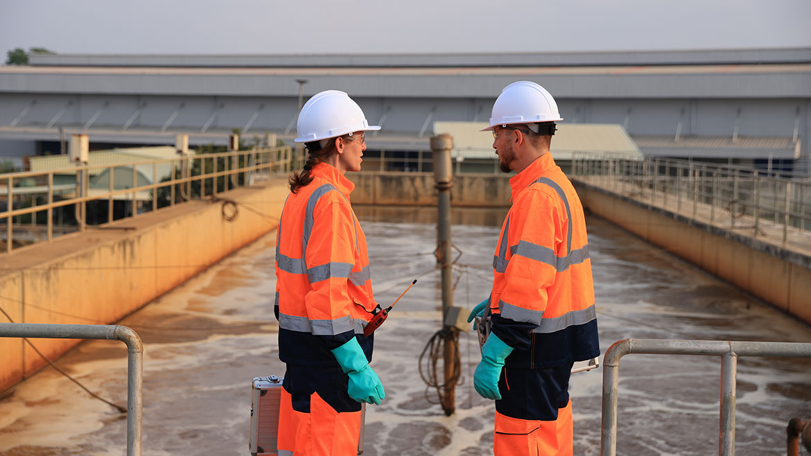 Safety and environmental engineers working at a wastewater treatment plant checking the quality of the water.
