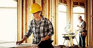 Woman architect looking over blueprints Woman architect looking over blueprints at home construction site.