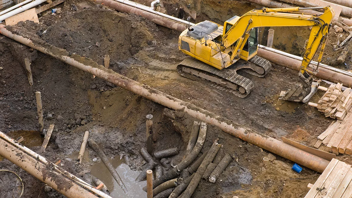 A overhead view of a digger and an excavation at an urban construction site.