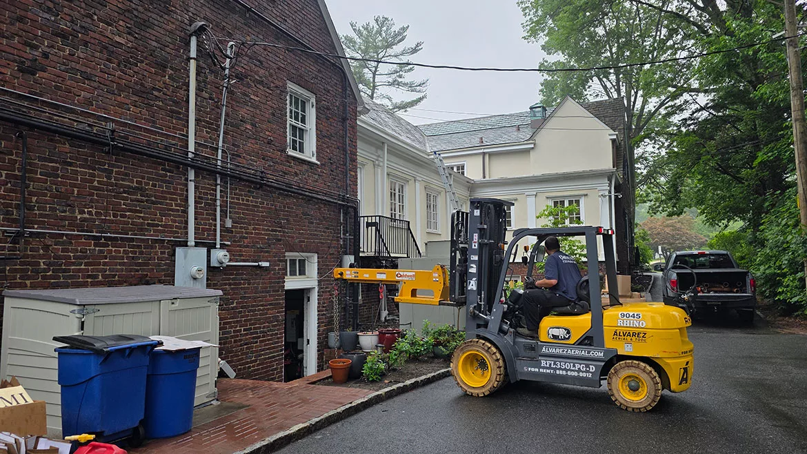 A rented forklift with boom extension outside of a home during a historic boiler replacement.