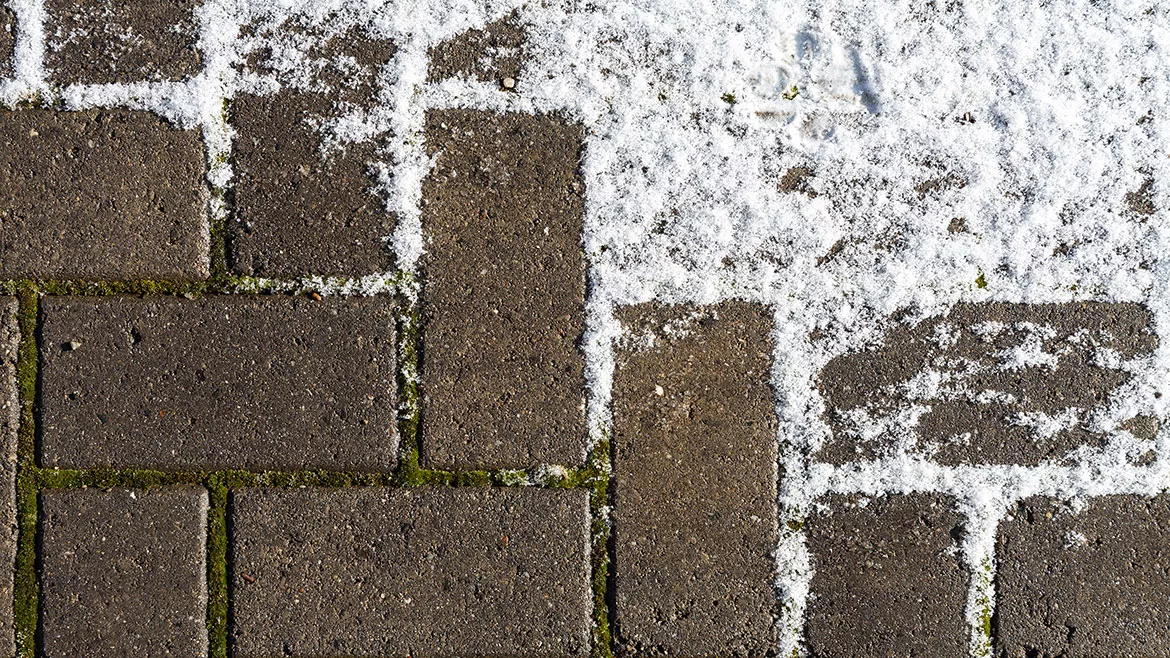A concrete walkway partially covered with light snow.