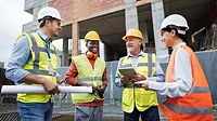 A varied group of workers performs site analysis at the construction site
