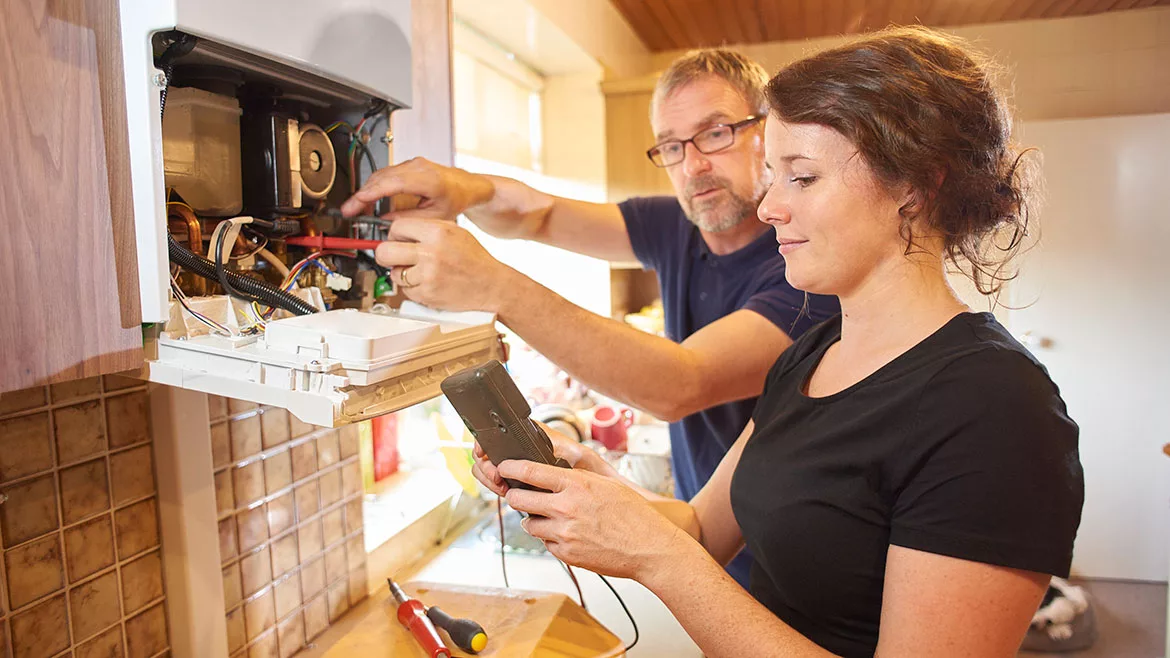 Female plumbing contractor with her boss servicing a boiler