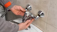 Plumber fixing faucet in a bathroom.